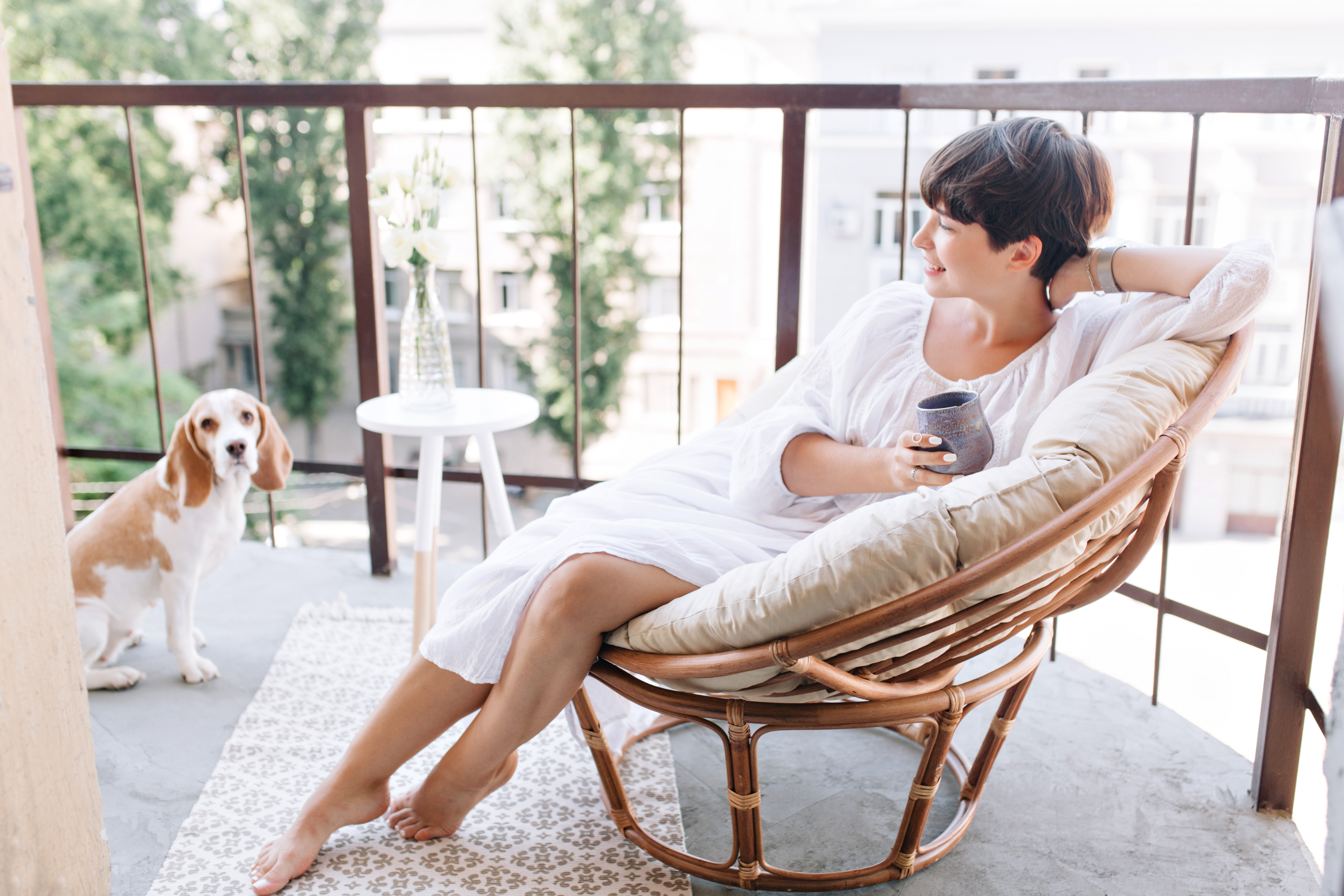 relaxed-barefooted-girl-white-dress-sitting-chair-balcony-holding-cup-tea (1)